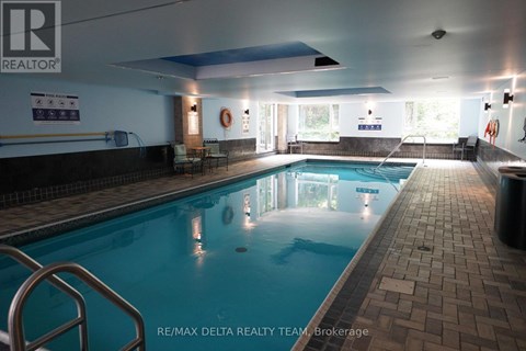 A large indoor swimming pool with a REALTOR® sign on the wall.