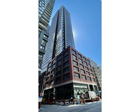 A tall building with a glass facade stands in front of a shorter building with a brick facade.