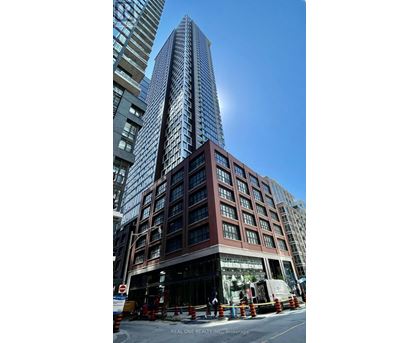 A tall building with a glass facade stands in front of a shorter building with a brick facade.