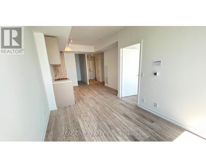 A spacious room with wooden flooring and white walls, with a cabinet and a door visible.