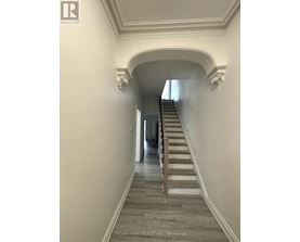 A hallway with a staircase and a brokerage logo.