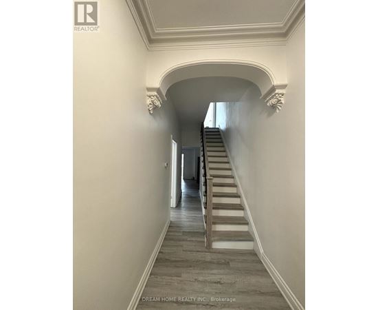 A hallway with a staircase and a brokerage logo.