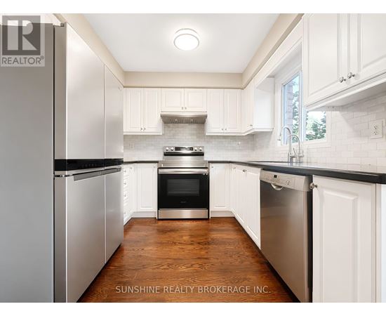 A kitchen with white cabinets and a wooden floor.
