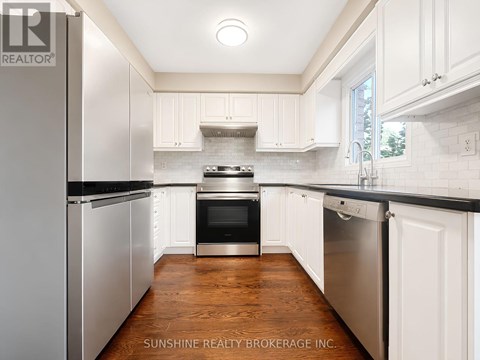 A kitchen with white cabinets and a wooden floor.