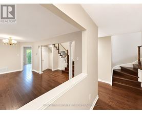 A spacious room with wooden floors and a staircase.