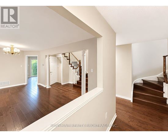 A spacious room with wooden floors and a staircase.