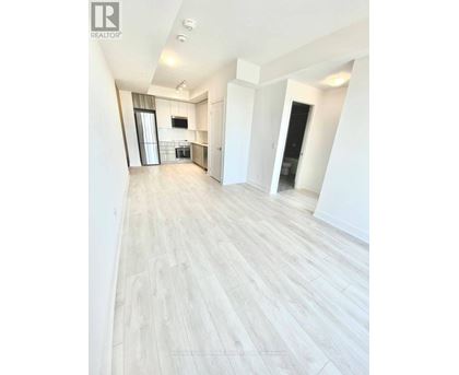 A spacious room with light wood flooring and white walls.