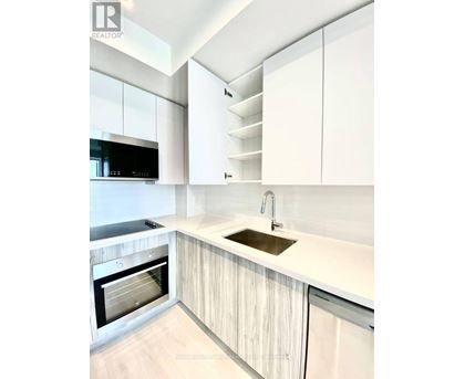 A modern kitchen with white cabinets and a wooden floor.
