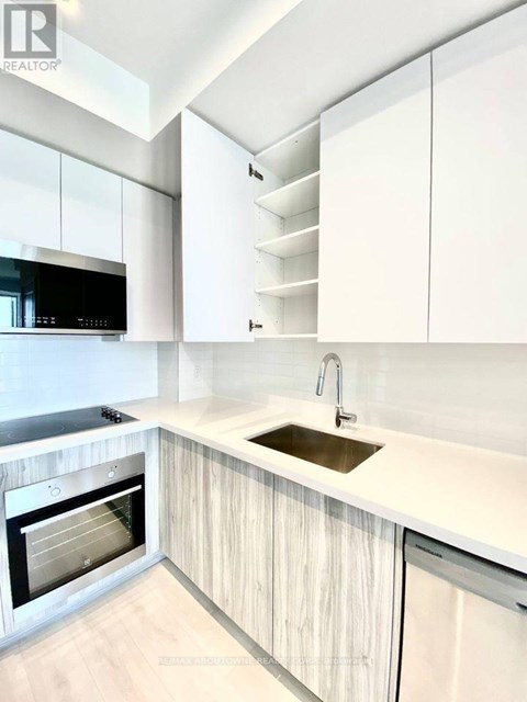 A modern kitchen with white cabinets and a wooden floor.