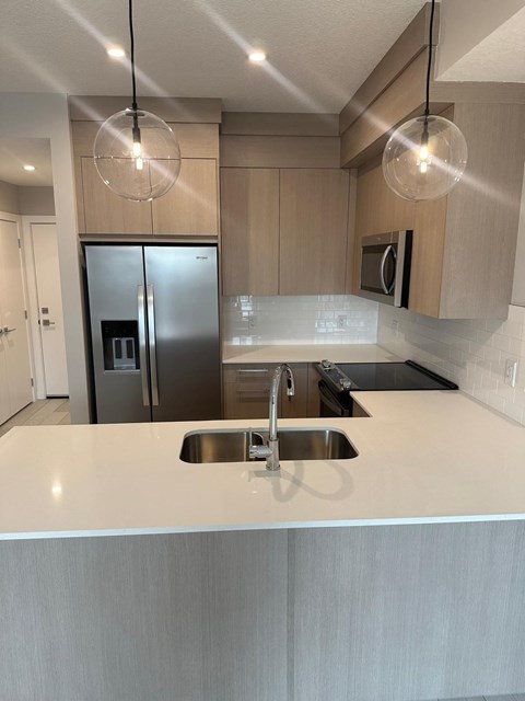A modern kitchen with a stainless steel refrigerator and a sink.