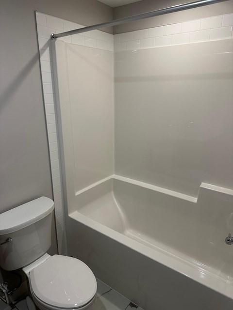 A white toilet sits next to a white bathtub in a bathroom.