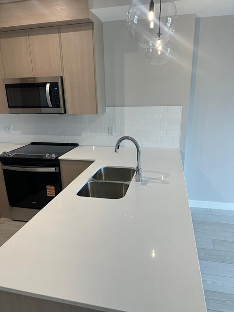 A modern kitchen with a white countertop and a black stove.