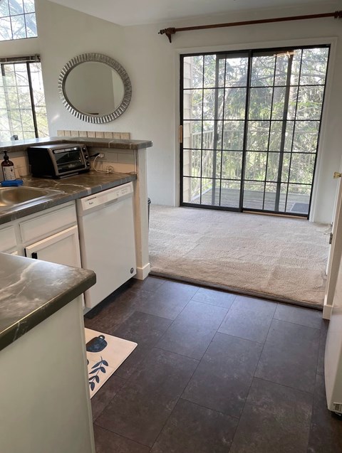 A kitchen with white cabinets and a black counter top.