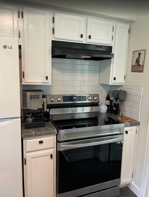 A kitchen with a stove top oven and a refrigerator.