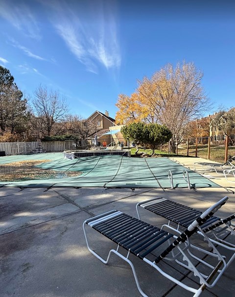 A pool with a green cover and a bench in front of it.