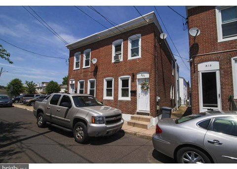 A silver truck is parked in front of a brick house.