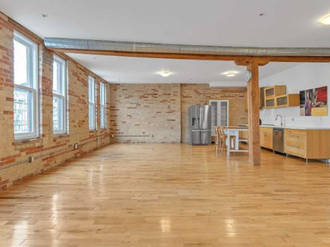 A room with wooden floors and exposed brick walls.