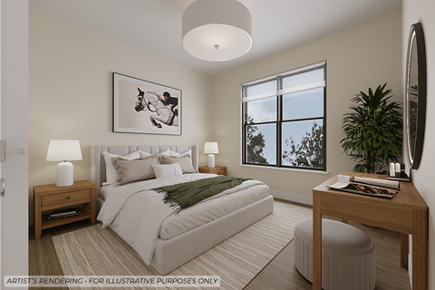 A bedroom with a large bed, a side table with a lamp, a window with a view of trees, and a potted plant.