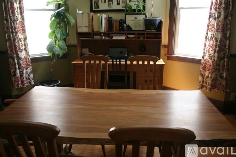 A wooden table with chairs in front of a bookshelf.