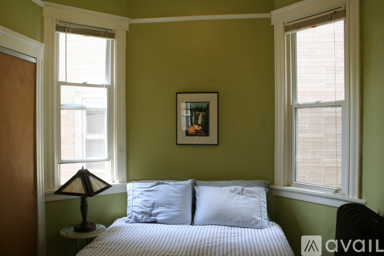 A bedroom with a bed, a lamp, and a picture on the wall.