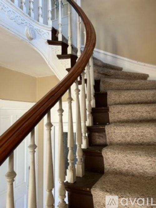 A staircase with a white balustrade and beige carpeted steps.