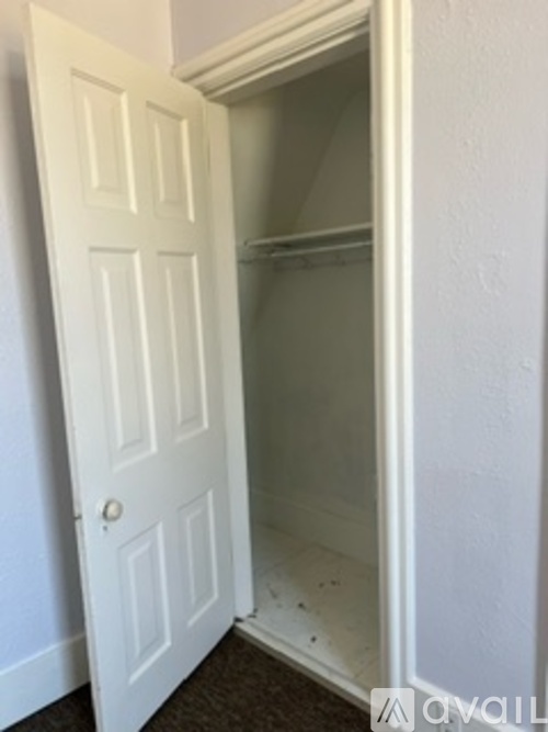 A white door is open to a small, empty room.