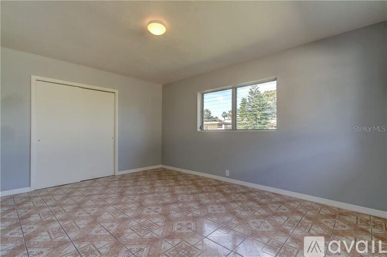A room with a tiled floor and a window showing trees outside.