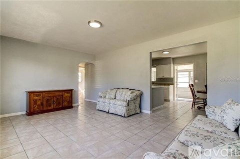 A spacious living room with a white sofa and a wooden cabinet.