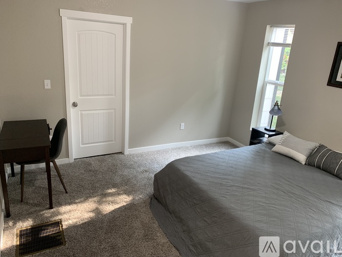 A bedroom with a bed, desk, chair, and window.