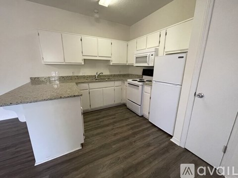 A kitchen with white cabinets and a granite countertop.