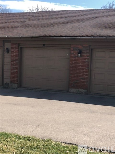 A garage with two doors is attached to a brick building.