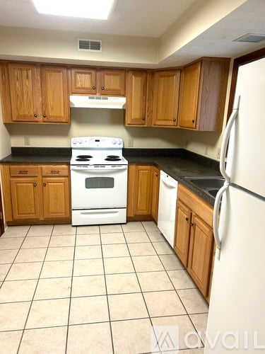A kitchen with wooden cabinets and a white stove top oven.