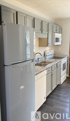 A kitchen with a white refrigerator and white cabinets.