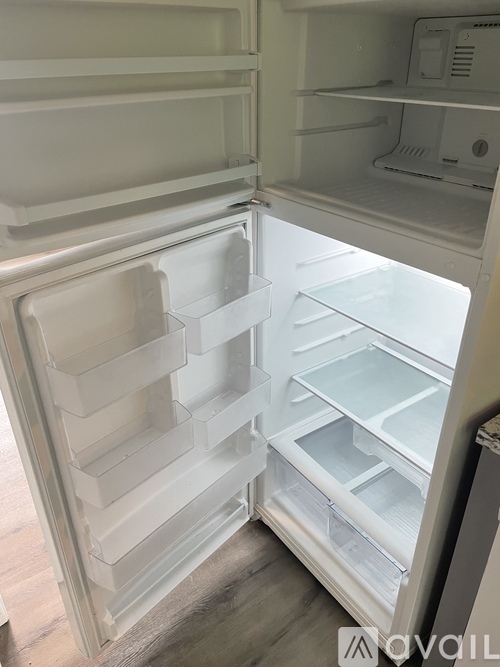 A white refrigerator with the door open and empty.