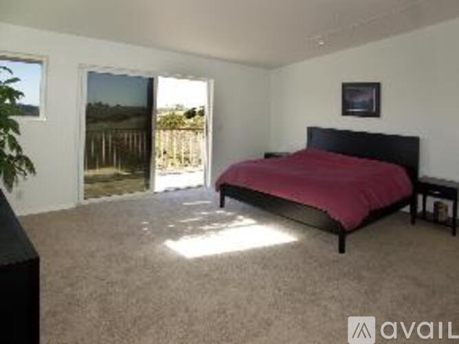 A bedroom with a red bedspread and a black headboard.