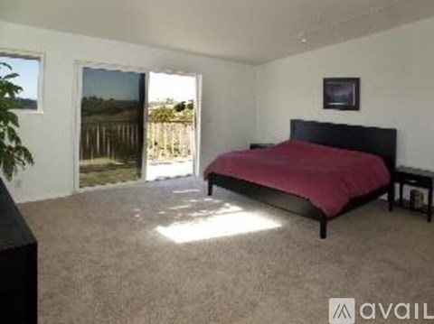 A bedroom with a red bedspread and a black headboard.