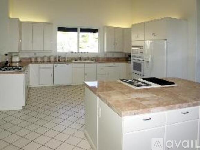 A kitchen with white cabinets and a marble countertop.