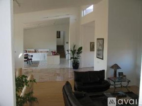 A living room with a black couch and a glass table.