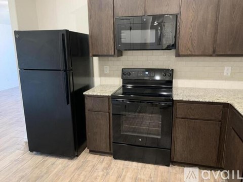 A black fridge and oven in a kitchen with wooden cabinets.