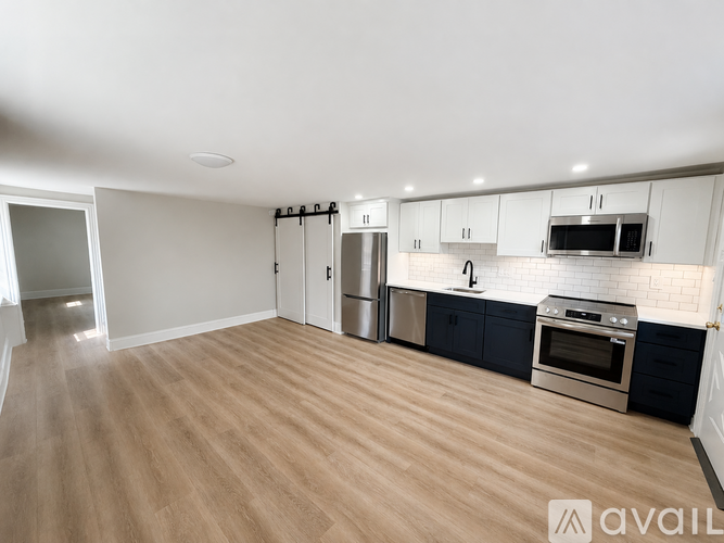 A kitchen with wooden flooring and stainless steel appliances.
