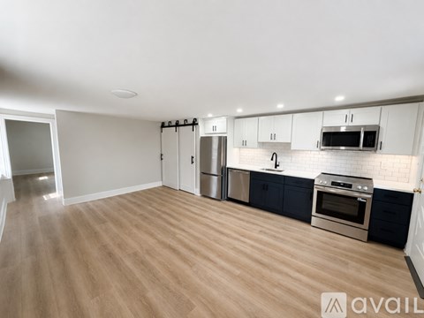 A kitchen with wooden flooring and stainless steel appliances.