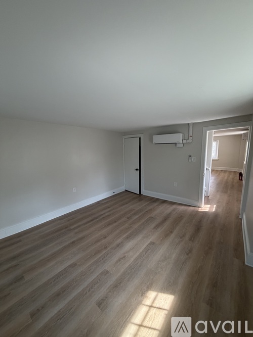 A room with wooden flooring and a door on the left side.
