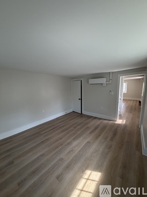 A room with wooden flooring and a door on the left side.