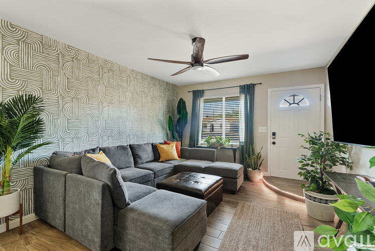 A living room with a grey couch and a ceiling fan.