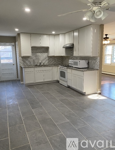 A kitchen with white cabinets and a grey floor.