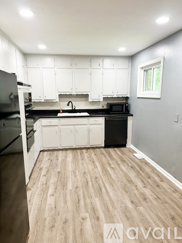 A kitchen with white cabinets and a black refrigerator.