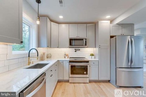 A modern kitchen with white cabinets and stainless steel appliances.