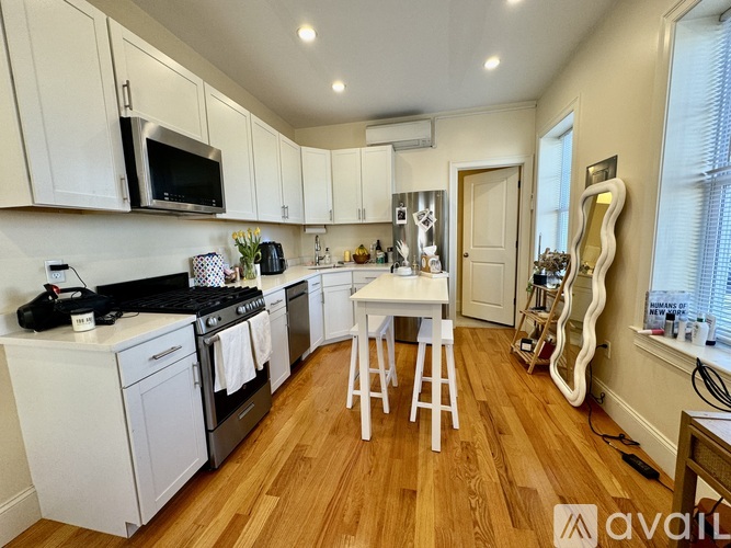 A kitchen with white cabinets and a wooden floor.