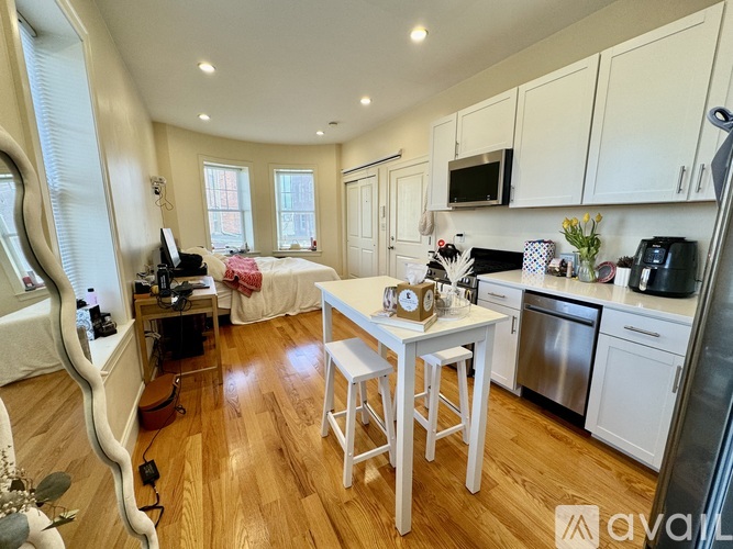 A kitchen with white cabinets and a wooden floor.