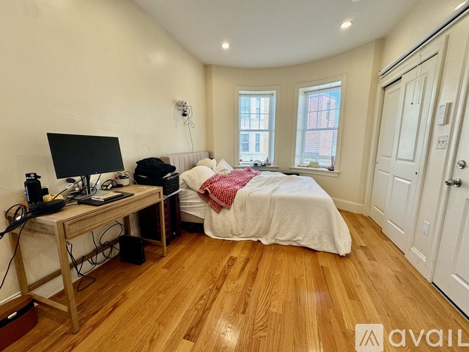 A bedroom with a bed, desk, and window.